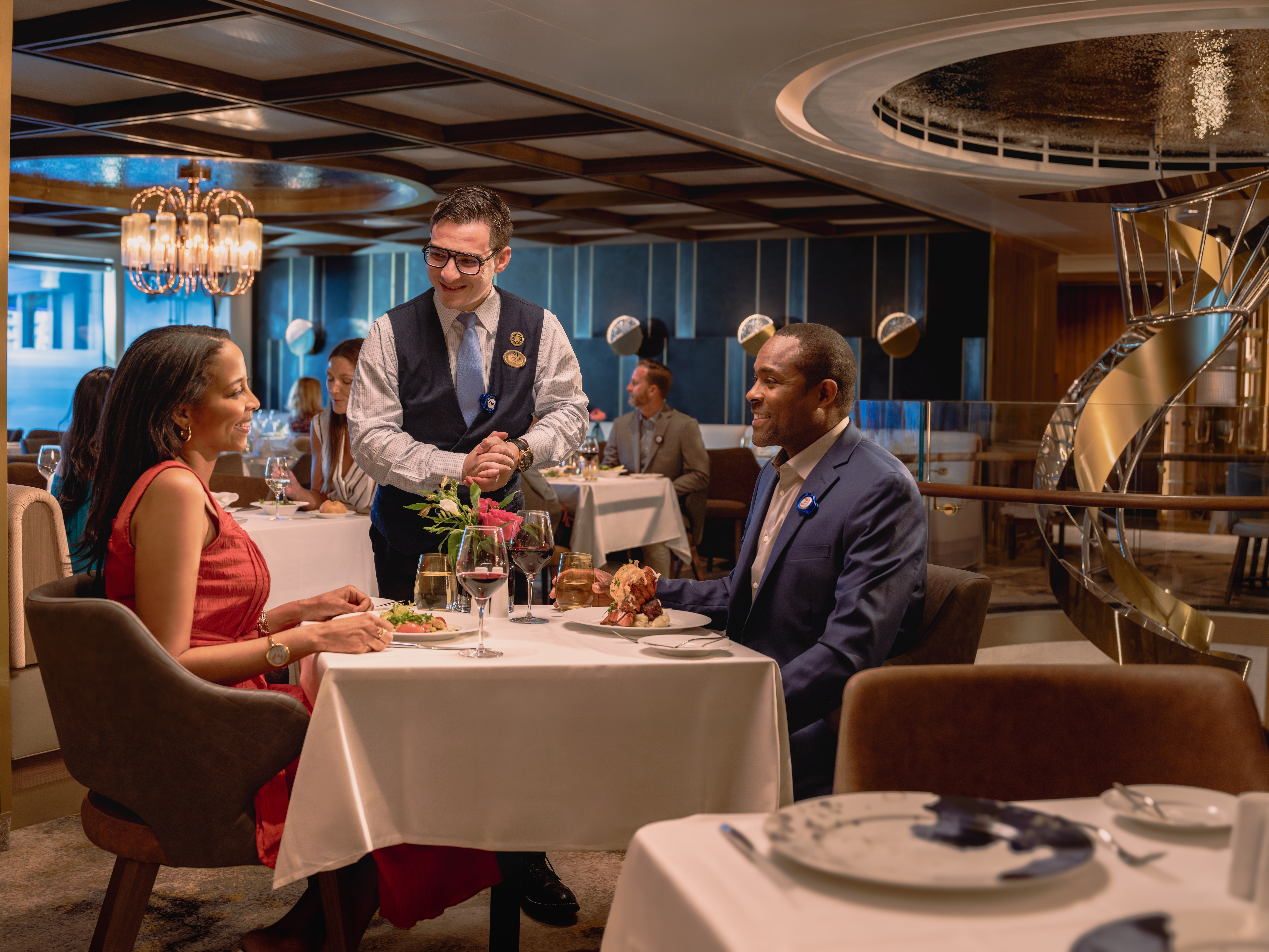 Two people sitting at a restaurant with the waiter taking their order